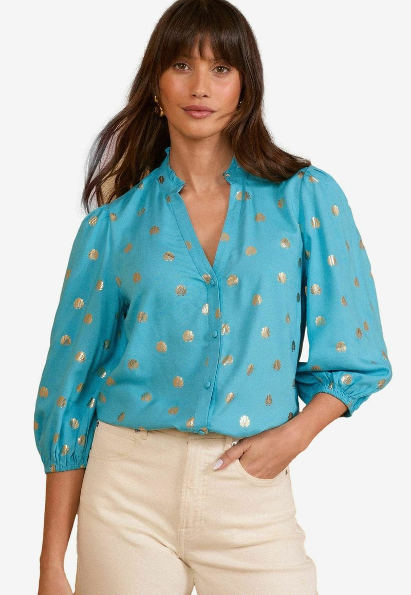Blusa teal con accenti in oro a motivo conchiglia, chiusura con bottoni e polsini arricciati. Tessuto morbido, leggero e vestibilità casual.