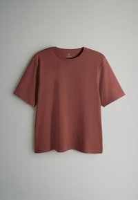 Kortärmad t-shirt med rund hals i rostfärg, tillverkad av mjukt tyg med en slät textur och en avslappnad passform. Inga synliga mönster eller detaljer i metall.