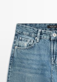 Blue denim jeans with front pocket, belt loop, metal button, and Massimo Dutti label on waistband against white background.