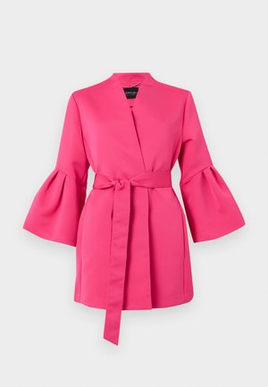 Robe portefeuille rose vif avec larges manches évasées et ceinture assortie à nouer à la taille, sur fond uni.