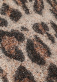 Løveprint tekstil i nuancer af beige, brunt og sort. Blød, fuzzy tekstur med store, uregelmæssige pletter. Egnet til forskellige designs.