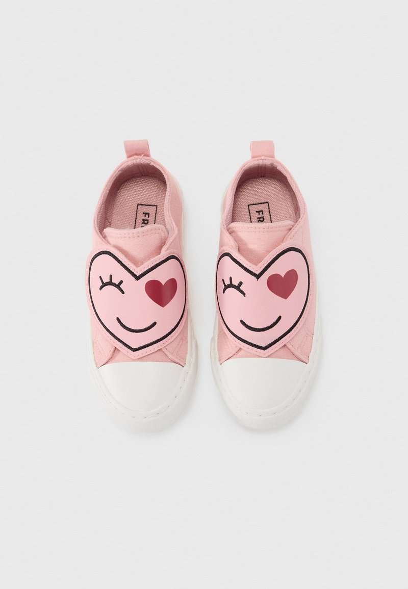 Chaussures roses pour tout-petit avec semelles blanches, chacune avec un visage coquin en forme de cœur avec un œil en cœur rouge sur le devant.