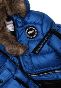 Blauwe pufferjack met een bontkraag, voorzien van een zwart logo-embleem, een zijlabel en ritszakken. Zachte, glanzende stof met gestikte panelen.