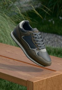 Lightweight athletic shoe in dark gray and olive. Features a smooth leather and mesh upper, round laces, and a cushioned sole.