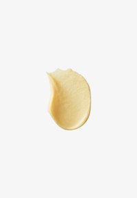 Muestra de un producto cosmético amarillo cremoso con una textura suave y semi-opaca, aplicada en forma redondeada sobre un fondo blanco.