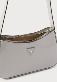 Borsa sintetica grigia con finitura lucida, caratterizzata da un logo triangolare argentato, scomparto con zip e tracolla a contrasto.