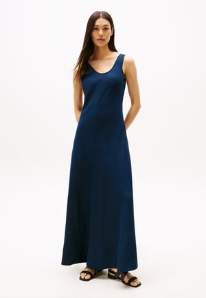 Abito maxi senza maniche di colore blu navy con scollo rotondo e una silhouette fluida, abbinato a sandali neri con cinturini. Texture liscia.