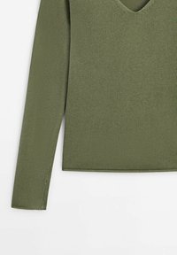 Pull vert tricoté à manches longues avec col en V, montré de la poitrine au poignet sur un fond blanc.