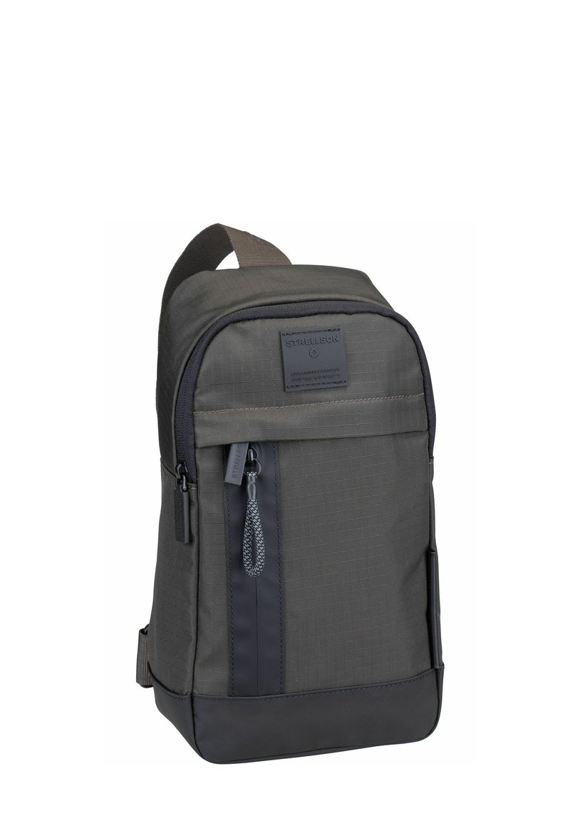 Grauer Rucksack aus strapazierfähigem Stoff mit strukturierter Oberfläche, ausgestattet mit einer vorderen Reißverschlusstasche und einem oberen Griff für einfaches Tragen.