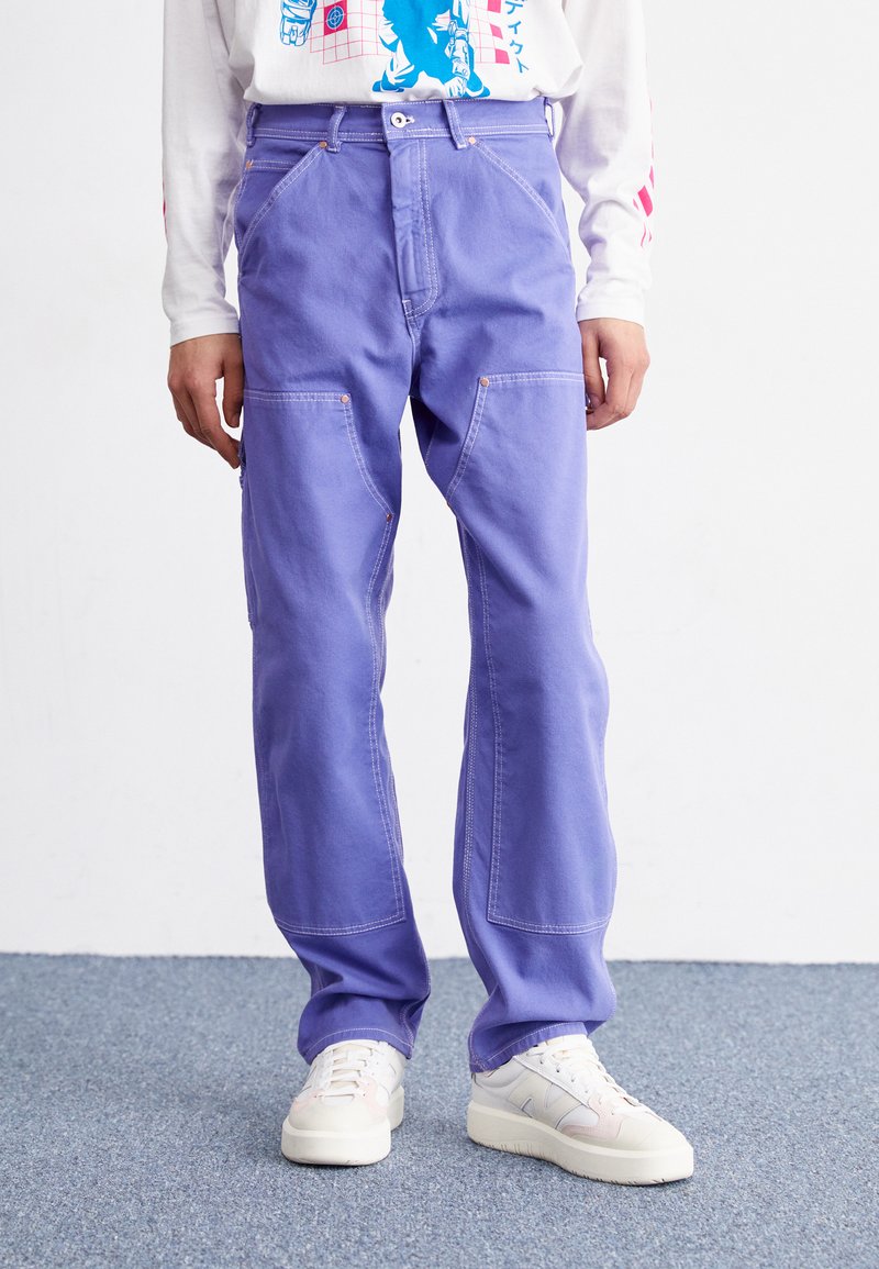 Light purple wide-leg pants made of cotton, featuring front pockets, visible stitching, and a relaxed fit, paired with white sneakers.