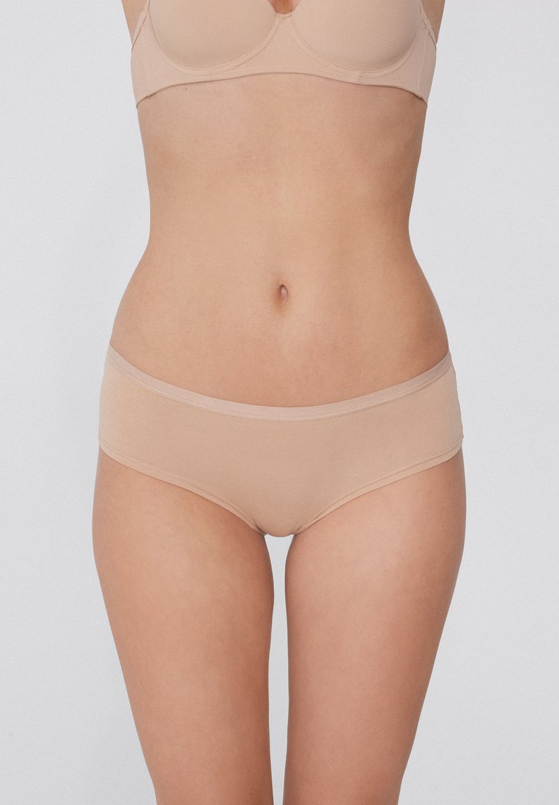 Beige bezešvé boxerkové kalhotky vyrobené z jemné, hladké látky. Nízký pas s pružným páskem a bez viditelných švů pro elegantní střih.