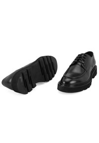 Chaussures en cuir noir avec une finition lisse, bout arrondi et un système de laçage. Semelle en caoutchouc épaisse avec des rainures peu profondes pour une meilleure adhérence.