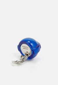 Llavero circular azul hecho de un material brillante con un gancho plateado. Presenta la marca grabada "Fiorucci" y una textura suave y brillante.