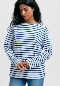 Pitkähihainen raidallinen paita valkoisena ja sinisenä. Ominaisuuksiin kuuluu venepääntie, rento malli ja hihansuut, joissa on kontrastiväriset yksityiskohdat.