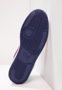 Sole tenisky Puma s fialovým gumovým designem, vlnovým vzorem a logem, s texturou pro lepší přilnavost a odolnost.