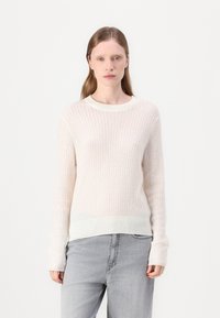 Lys beige ribbet genser med lange ermer og rund hals, med teksturert stoff og en litt lengre kant bak.