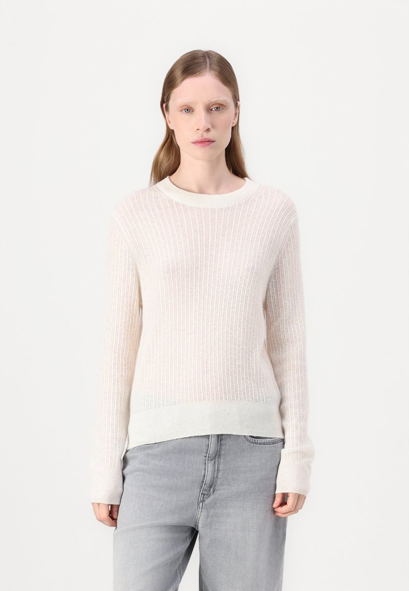 Lys beige ribbet genser med lange ermer og rund hals, med teksturert stoff og en litt lengre kant bak.