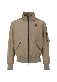 Beige bomberjack met een hoge kraag, sluiting met een rits aan de voorkant, twee grote zijzakken en één ritszak op de arm. Ribgebreide manchetten en onderkant.