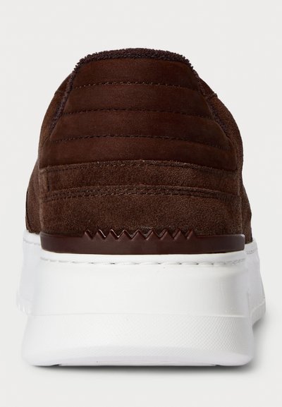 Adidași din suede maro, cu spatele căptușit și talpă din cauciuc alb, având detalii zigzag deasupra călcâiului.