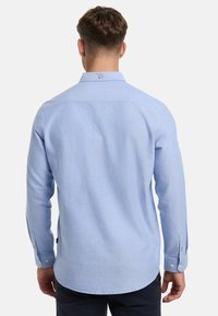 Camicia a maniche lunghe azzurro chiaro in cotone, con colletto classico, polsini con bottoni e una finitura leggermente texturizzata.