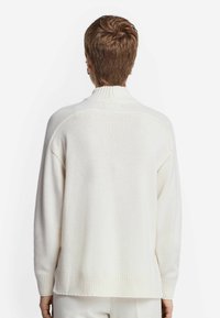 Cremefarbener, gestrickter Pullover mit hohem Kragen, gerippten Bündchen und Saum. Bietet eine großzügige, lässige Passform und weiche Textur.