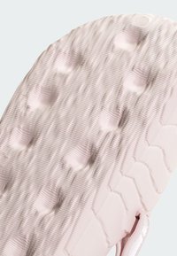 Podošva topánky s textúrovaným povrchom, v svetloružovej farbe, s hexagonálnymi a kruhovými vzormi a vyvýšenými bodkami pre trakciu.