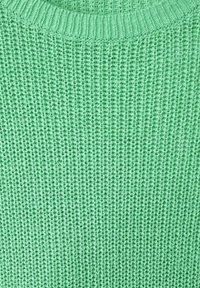 Green knitted sweater with a textured pattern, featuring a round neckline and a loose weave, providing a soft appearance.
