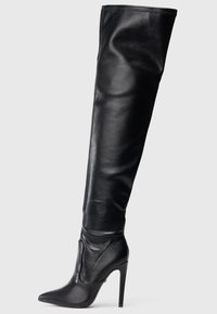 Fekete bőr, combfőig érő csizma hegyes orral és magas, tűs sarokkal. Simább textúrájú és testhezálló kialakítás, minimális hardverrel.