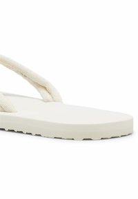 Infradito bianchi con suola piatta e superficie testurizzata. Presentano cinturini in tessuto intrecciato. Il design è minimalista con una finitura liscia.