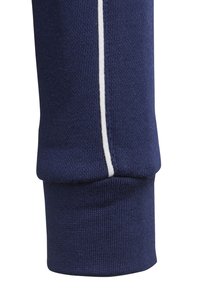 Polsino di indumento blu navy con una trama a coste e una striscia bianca a contrasto lungo la cucitura, che offre un dettaglio pulito e distinto.