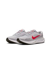 Sneaker sportive grigio chiaro con suola scura, dettagli rossi, tomaia in rete testurizzata e tallone arrotondato. Presentano lacci e un logo prominente.