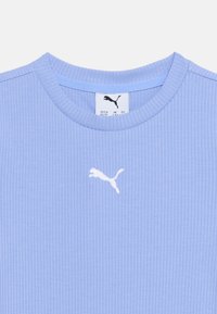 Φωτεινό γαλάζιο ριμπ μπλουζάκι με λαιμόκοψη και λευκό λογότυπο Puma στο κέντρο κάτω από το στρίφωμα του λαιμού, και ετικέτα μεγέθους ορατή μέσα στη λαιμοκοπή.