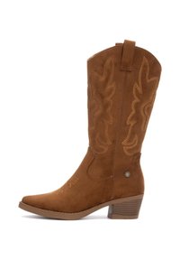 Bota vaquera de ante marrón con costuras intrincadas, punta afilada y tacón apilado. Presenta una pestaña para la sujeción y patrones decorativos en el cañón.