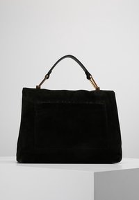 Czarna torebka z zamszu o miękkiej fakturze, prostokątnym kształcie, płaskiej przedniej kieszeni oraz krótkim skórzanym uchwycie z ozdobami w kolorze złota.