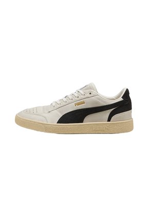 Sneaker Puma basse bianche e nere con suola beige, chiusura con lacci e logo Puma dorato sul lato e sulla suola.