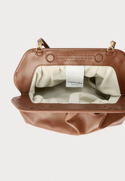 Καφέ δερμάτινη τσάντα χειρός με εσωτερικό από κρεμ ύφασμα, χρυσά κούμπωμα και εσωτερική ετικέτα που γράφει "THEMOIRÈ Made in Italy."