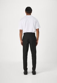 Vit kortärmad t-shirt och svarta byxor, med bakfickor och slim fit. Svarta skor fulländar outfiten. Enkel, minimalistisk design.