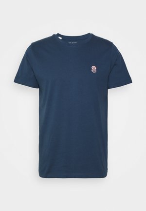 T-shirt en coton bleu marine avec un col rond. Présente une petite broderie de méduse rose sur la poitrine gauche. Manches courtes, coupe régulière.