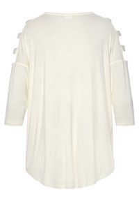 Witte relaxte top met driekwart mouwen, voorzien van uitsparingen op de schouders en een zachte, gladde textuur. Gebogen zoom aan de achterkant.