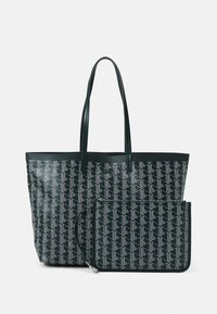 Grand sac fourre-tout vert foncé avec un motif géométrique blanc, doté de longues poignées et d'une pochette assortie amovible avec fermeture éclair.
