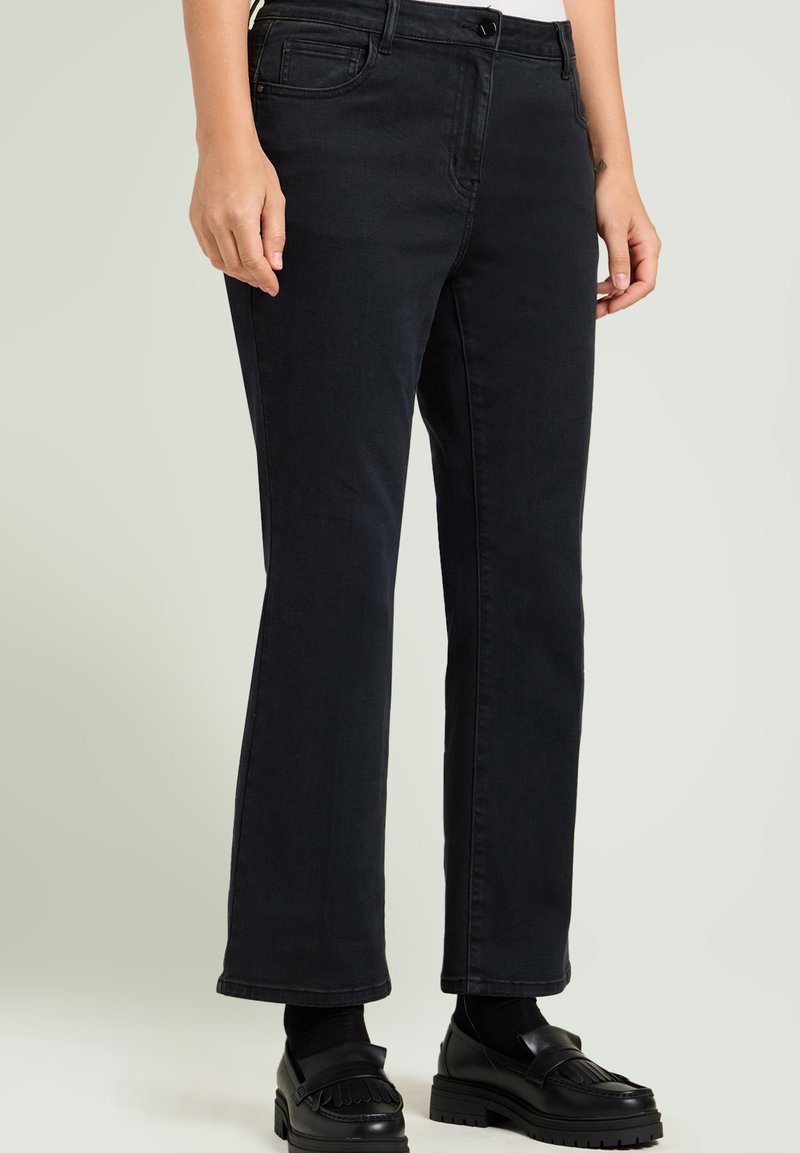 Zwarte denim broek met een recht gesneden ontwerp, vijf zakken en subtiele stiksels. Gecombineerd met zwarte instappers voor een complete look.