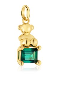Złoty wisiorek w kształcie misia trzymającego prostokątny, szmaragdowo-zielony kamień szlachetny z wypolerowanym wykończeniem oraz pętelką do łańcuszka.