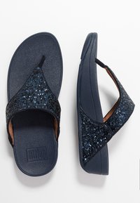 Marineblå flip-flops med teksturert såle, som har et glitrende svart og blått glitrende reim. Polstret såle for komfort.
