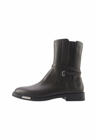 Schwarze Lederknöchelschuh mit glatter Oberfläche, Riemendetail um den Knöchel und quadratförmiger Spitze. Verfügt über einen niedrigen Blockabsatz und ein Metall-Logoprinzip.