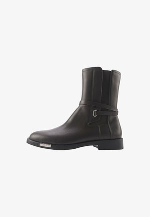 Must mustade nahkjalatsid siledast tekstuurist, rihmaga ümber pahkluu ja ruudukujuline ninaga. Omab madalat plokknööriga kõrgust ja metallist logo aktsenti.