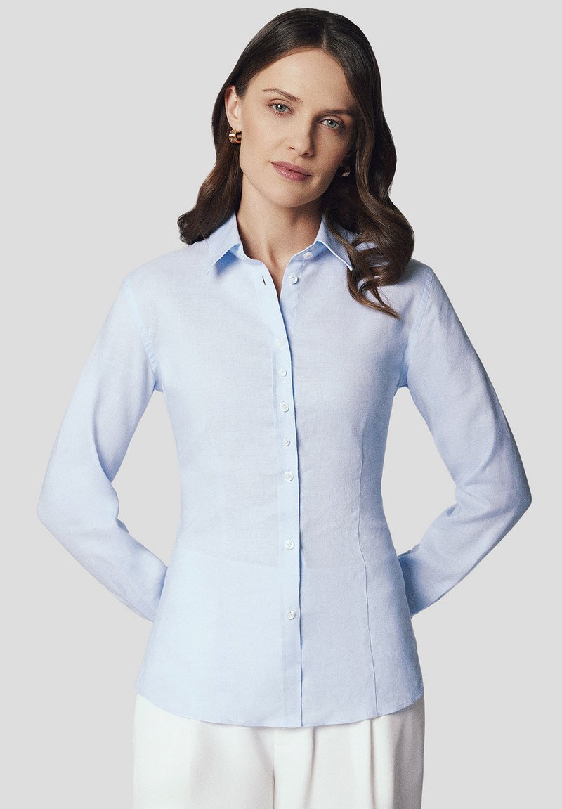 Jasnoniebieska, długosleeve koszula z lnu o wyraźnym kołnierzyku, zapięciu na guziki i dopasowanym kroju. Gładka faktura z widocznymi guzikami.