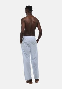 Pantalons de pyjama rayés en bleu clair avec une taille élastique, coupe ample et une texture subtile, vus de dos.