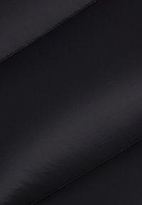 Tissu noir avec une texture lisse et brillante. Le matériau semble léger et a un éclat subtil. Coutures visibles le long des bords.
