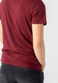 Bordowy t-shirt z krótkim rękawem wykonany z miękkiej bawełny, o dopasowanym kroju, z okrągłym dekoltem i gładką fakturą.