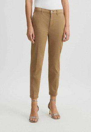 Bruine tapered broek van textuurstof, met een sluiting aan de voorkant en zijzakken, gecombineerd met geprinte hakken met bandjes.